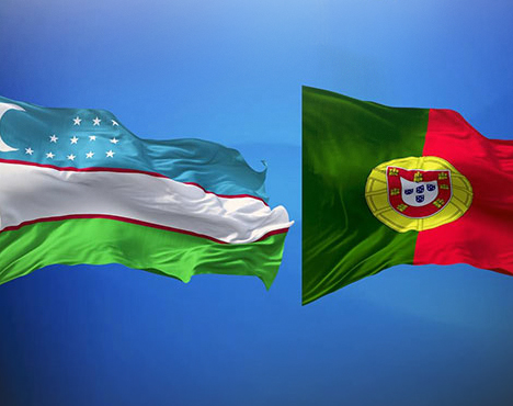 На изображении представлены два развевающихся на фоне голубого неба флага: флаг Узбекистана слева и флаг Португалии справа