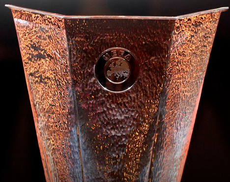 Медный вазон с тиснением и логотипом в центре на темном фоне